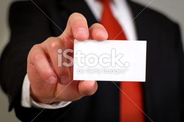 A businessman in a suit holds a blank white business card that is ready for your logo!